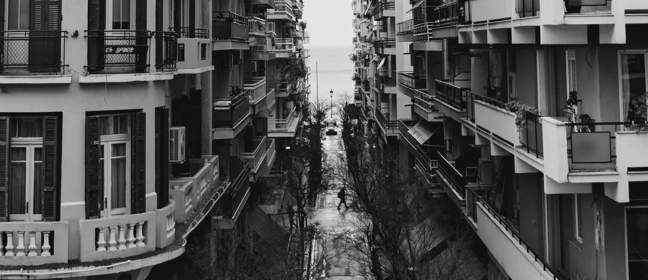 Στενός δρόμος με πολυκατοικίες οδηγεί στη θάλασσα, ασφάλεια σπιτιού από φυσικές καταστροφές