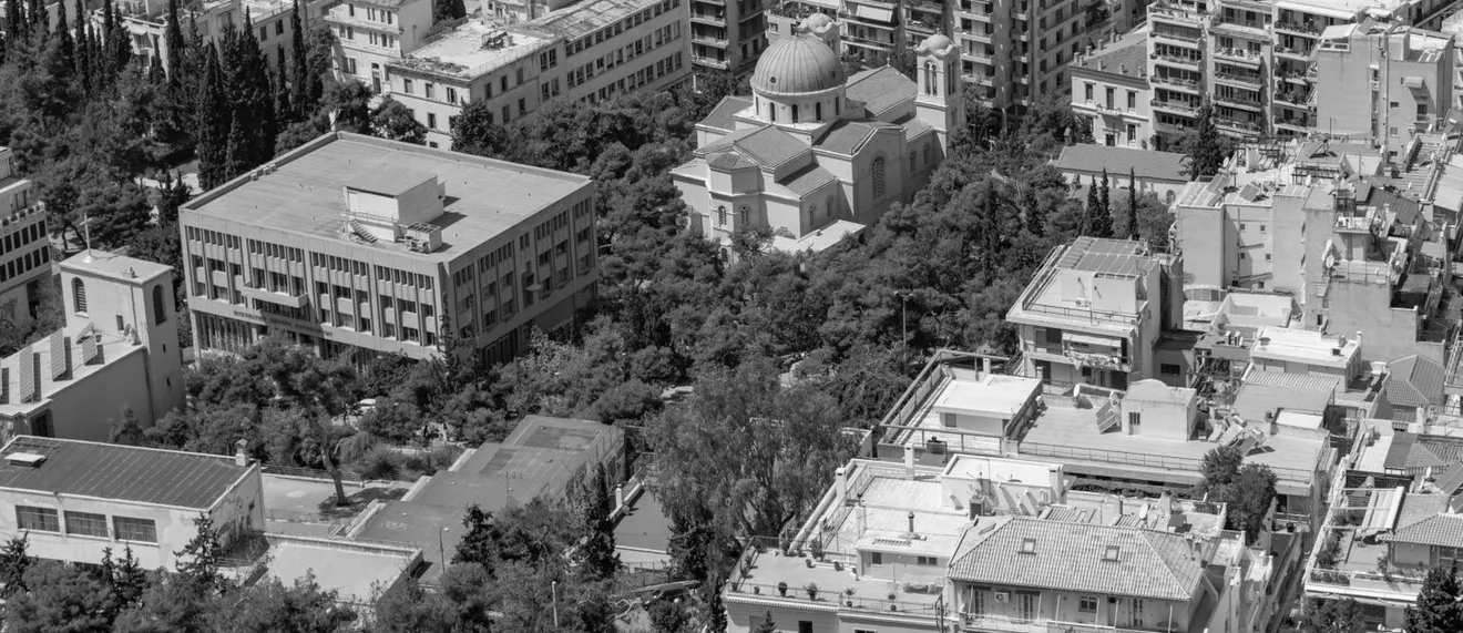 Ασπρόμαυρη εικόνα αστικής περιοχής με κτίρια, μια ορθόδοξη εκκλησία με τρούλο και δέντρα γύρω από τις κατασκευές.
